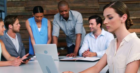 Dedicated Businesswoman Working on Laptop in Busy Office