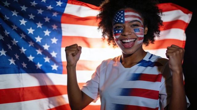 Triumphant fan wearing american flag face paint celebrating victory with raised fists