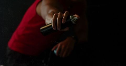 Hand Holding Aerosol Spray Can in Dim Lighting