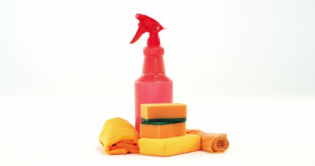 This image shows essential cleaning supplies placed on a white background, including a red spray bottle, a sponge, and orange cloths. It is suitable for illustrating household cleaning routines, cleaning product advertisements, hygiene and sanitation guides, and articles about housekeeping.