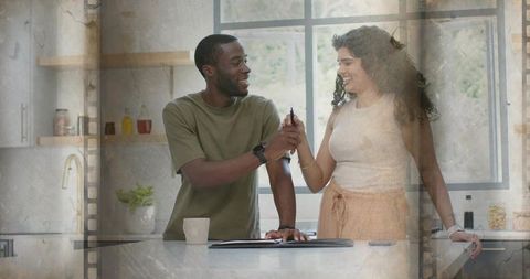 Smiling couple exchanging keys at sunlit modern kitchen island, celebrating joyful new home