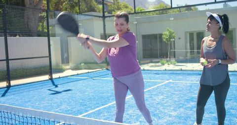 Padel players practicing forehand on bright blue court during outdoor coaching session