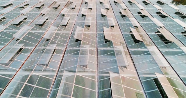 A modern building's glass facade creates a pattern of reflections and geometric shapes, with copy space. Its design showcases contemporary architecture and the use of glass to enhance aesthetic appeal.