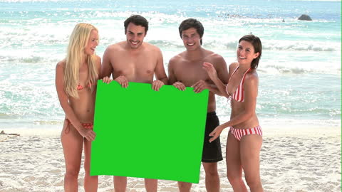 Group Holding Green Screen on Sunny Beach