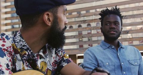 Two young men having conversation with guitar on rooftop patio