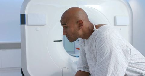 African male patient leaning into ct scanner wearing hospital gown in diagnostic radiology