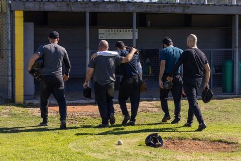 Baseball teammates walking to dugout after inning carrying gloves and helmets, unity