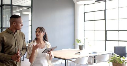 Colleagues Discussing Strategy in Modern Office Holding Tablet