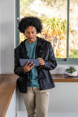 African American man using tablet while leaning on kitchen counter with terrarium