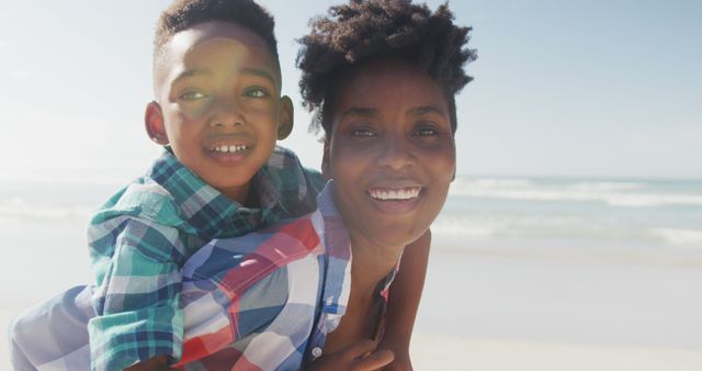 Mother and son spending quality time together on a sunny beach. Ideal for advertisements about family vacations, summer activities, or outdoor leisure and bonding experiences.