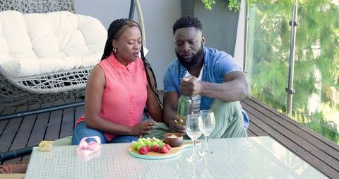 African Couple Relaxing on Patio with Fruits and Drinks