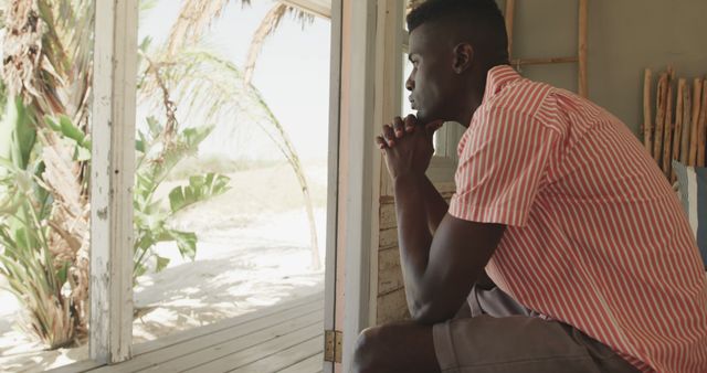 Contemplative Man Seated Indoors by Beach with Open Doorway - Download Free Stock Images Pikwizard.com