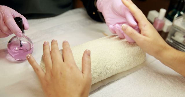 Nail technician painting top coat onto customers nails at the nail salon