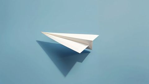 Sleek white paper airplane on calm blue background