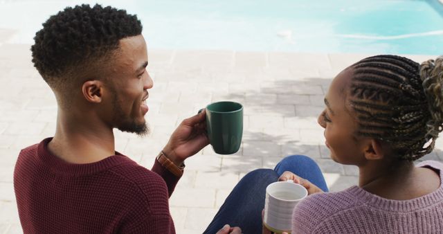 Happy african american couple embracing and relaxing with coffee outside house. Lifestyle, relationship, spending free time together concept.