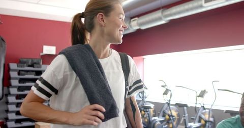 Fit Woman Preparing for Workout in Gym with Towel and Bottle