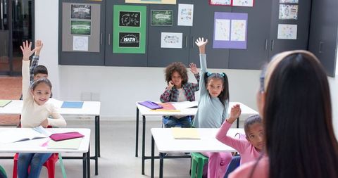 Students Raising Hands Enthusiastically in Classroom