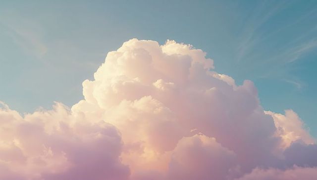 Towering cumulus cloud illuminated by soft pastel sunlight