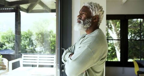 Pensive Senior Man Relaxing at Home by Sunlit Patio