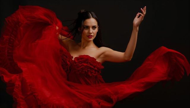 Elegant hispanic dancer in flowing red chiffon gown spinning gracefully