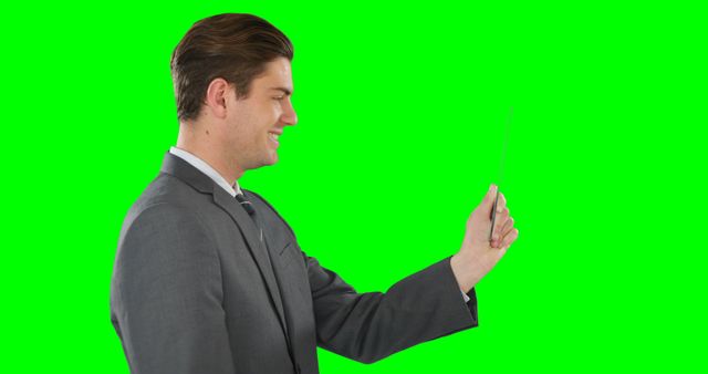 Businessman smiling and holding smartphone as if video calling, against a vibrant green screen background. Ideal for demonstrating video call technology, business communication, remote work, professional settings, and entrepreneur-related themes. Suitable for marketing materials, advertisements, website illustrations, and social media content related to business and technology.
