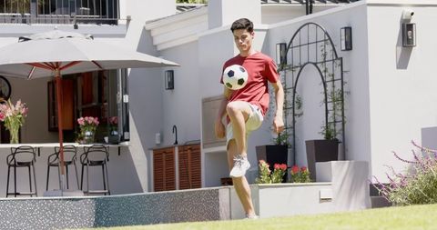 Biracial Man Practicing Football Skills in Sunny Tiered Garden