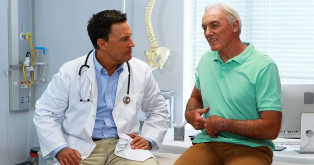 A Caucasian middle-aged doctor is engaging in a conversation with a senior Caucasian male patient in a medical office, with copy space. Their interaction suggests a consultation or discussion about the patient's health concerns or treatment options.