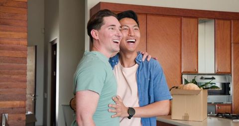 Happy Gay Couple Embracing in New Home Kitchen