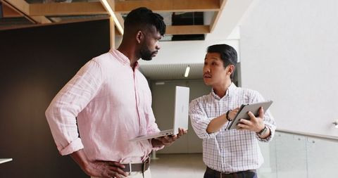 Two Professionals Collaborating with Laptop and Tablet in Modern Office