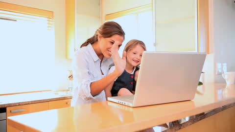 Mother and Daughter Smiling and Waving During Video Call at Home