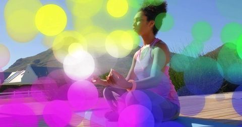 Meditating on sunlit deck in pink activewear, outdoor yoga mindfulness serenity
