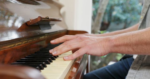 Caucasian man plays the piano at home, with copy space. Gentle fingers strike the keys during a peaceful music session.