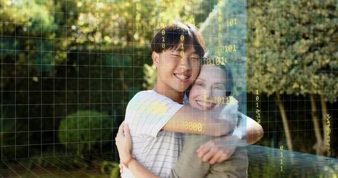 Smiling young couple hugging in backyard with augmented reality binary grid data overlay