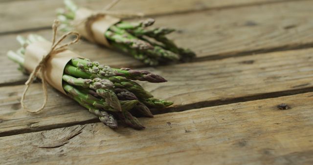 Image of two fresh asparagus bundles with copy space on wooden background. fusion food, fresh vegetables and healthy eating concept.