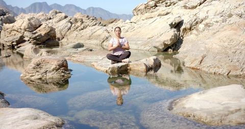 Woman Meditating on Rock by Serene Mountain Lake
