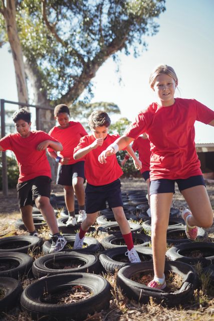 Kids running over tyres during obstacle course training in the boot camp