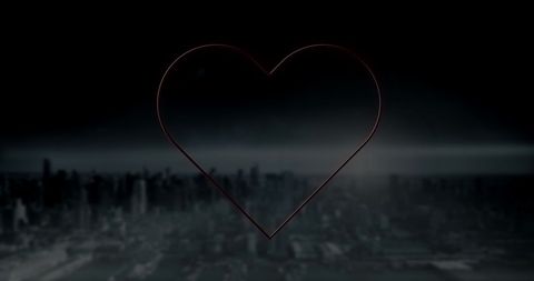 Neon Red Heart Glowing Over Dark Cityscape at Night