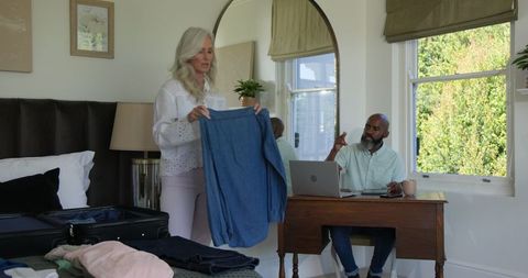 Couple packing for wedding day adventure, laptop on desk