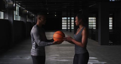 Fit Couple Sharing a Basketball Indoor Fitness Challenge