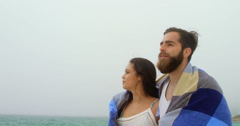 Romantic Couple Wrapped in Blanket Strolling on Misty Beach