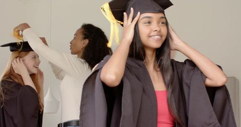 Young women adjusting graduation caps and yellow tassels celebrating academic success