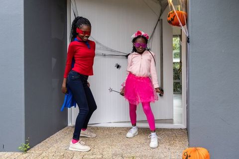African american preteen girls posing in colorful halloween costumes on decorated porch