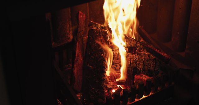 Burning logs in a fireplace creating a warm and cozy atmosphere, perfect for usage in storytelling about comfort at home, seasonal greeting cards, advertisements for home heating products, and articles on home decor. Image depicts a rustic hearth setting, emphasizing comfort, relaxation, and indoor warmth during winter.