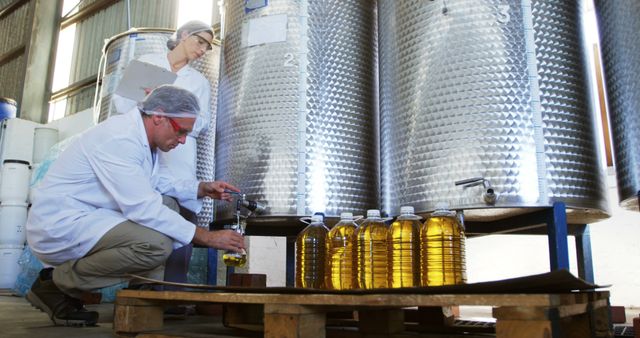 A middle-aged Caucasian man and woman, both professionals in lab coats, are inspecting and testing olive oil in a production facility, with copy space. Their meticulous quality control process ensures the olive oil meets industry standards before distribution.