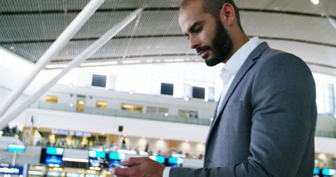 Business Professional Checking Phone at Modern Airport Terminal