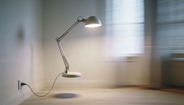 Shining silver adjustable lamp hovering above wooden floor in minimalist corner with cord