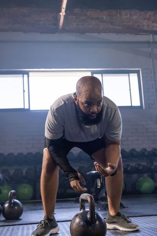 Focused athlete preparing to lift heavy kettlebell in industrial gym strength training
