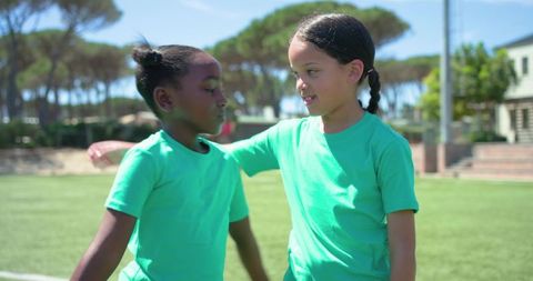 Youth soccer camaraderie embracing and smiling on field wearing matching green shirts