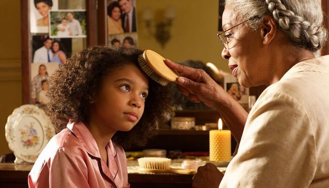 Grandmother brushing granddaughter curly hair at vanity candlelight, tender grooming ritual