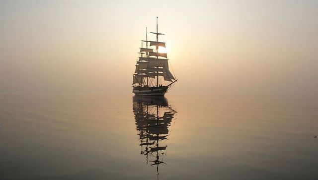 Majestic sailing ship at sunrise on serene waters